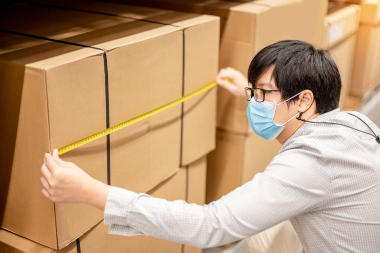 Warehouse worker measuring carton dimensions before international shipping